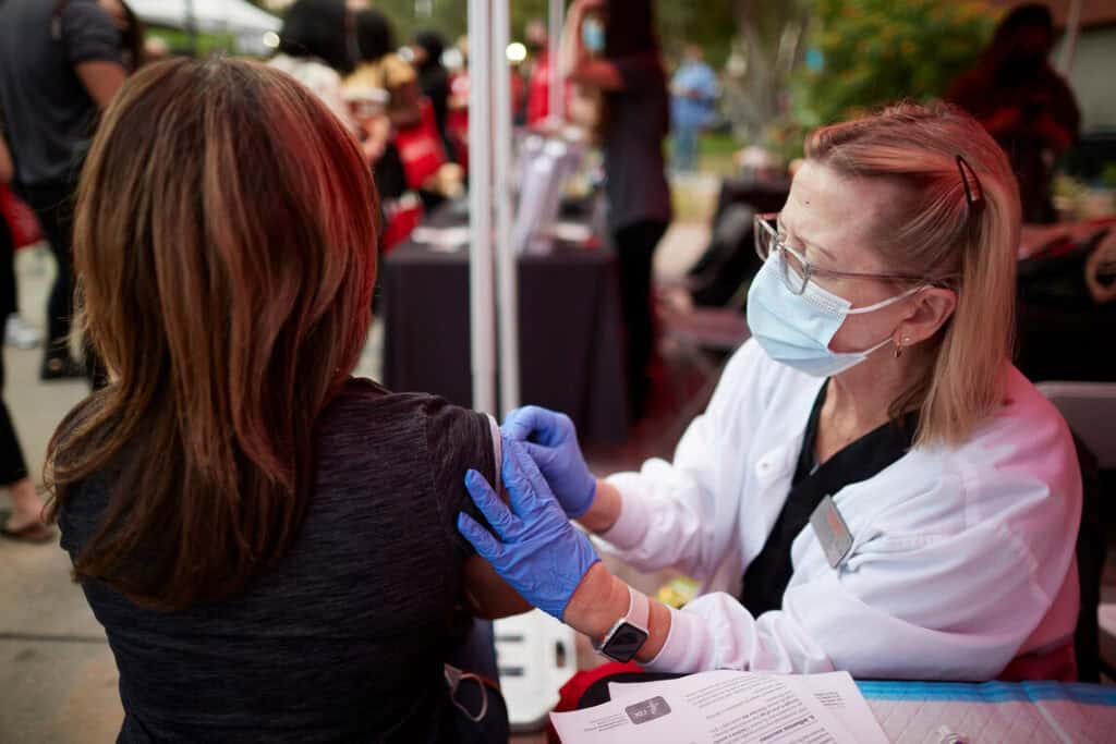 individual receiving a vaccination from masked health practitioner