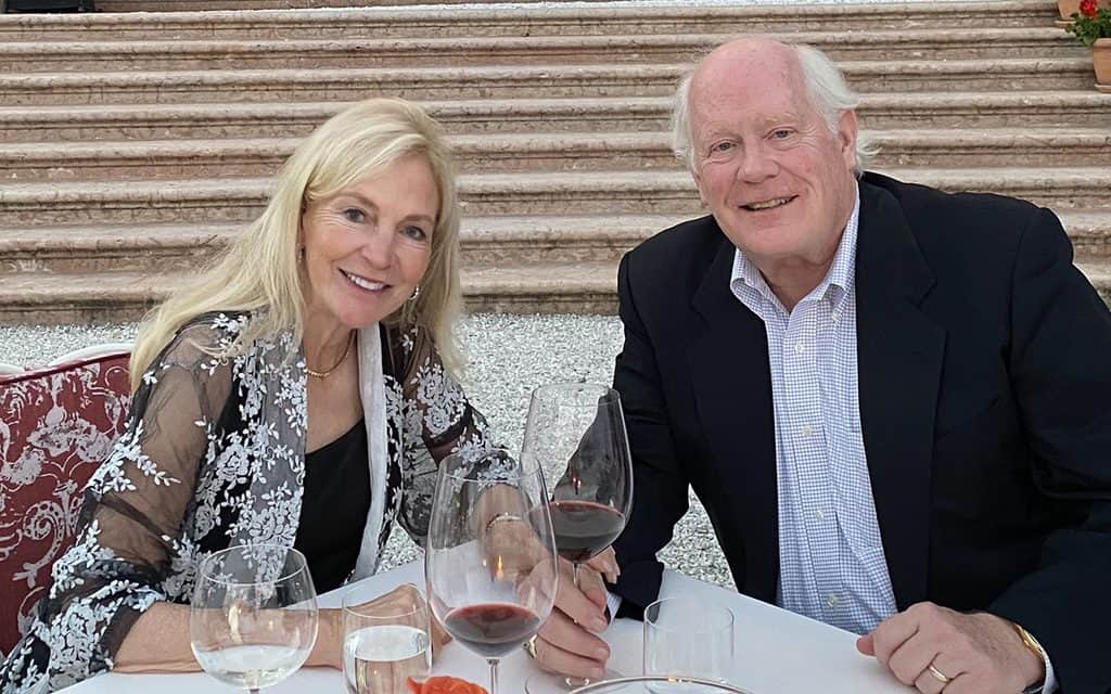 Linda DeBruce and Paul DeBruce seated at an elegantly set outdoor cafe table.