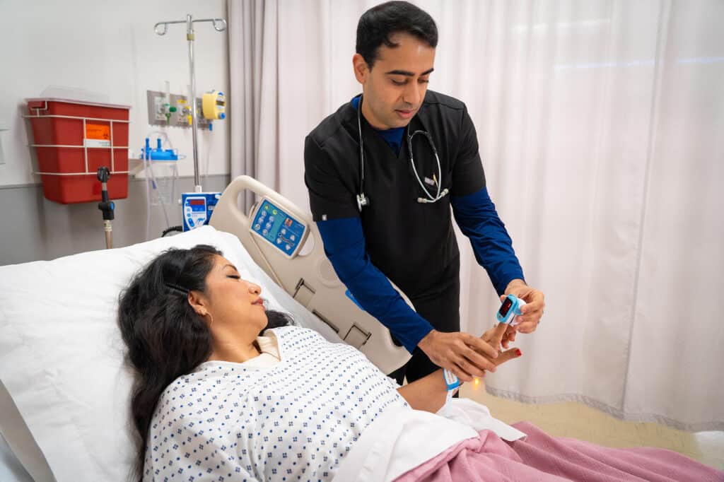 medical resident at the school of medicine, taking a woman's pulse.